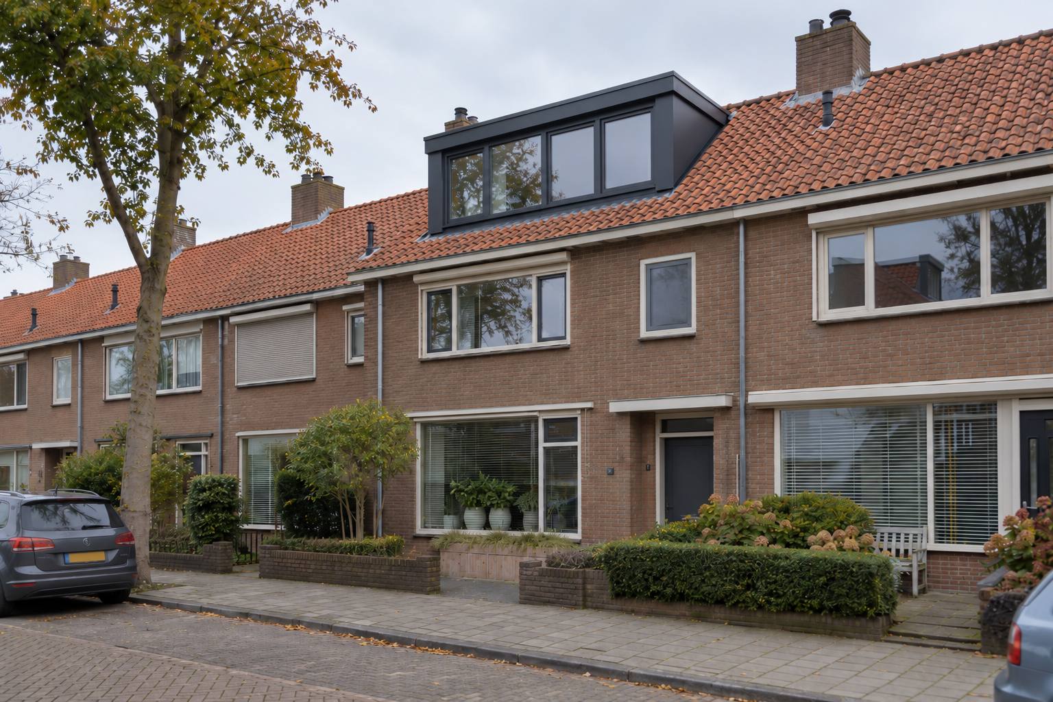 Rijwoning met een donkere dakkapel met vier ramen op het pannendak